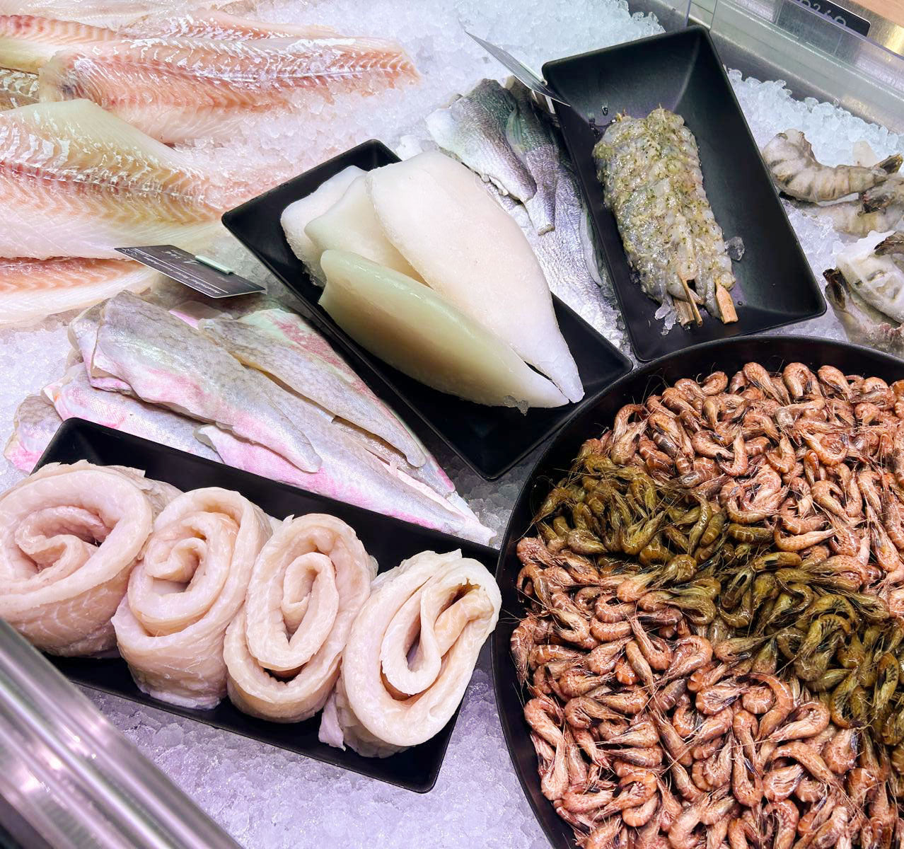 Frischer Fisch in schwarzen Thekenschalen