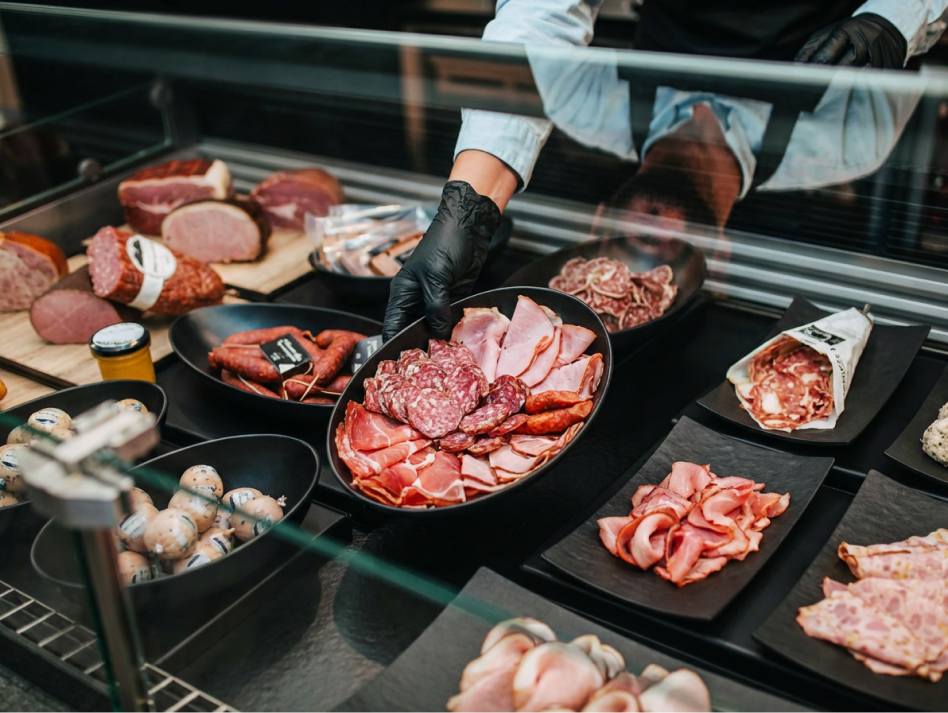 Verkäufer befüllt Metzgertheke mit schwarzen Thekenschalen