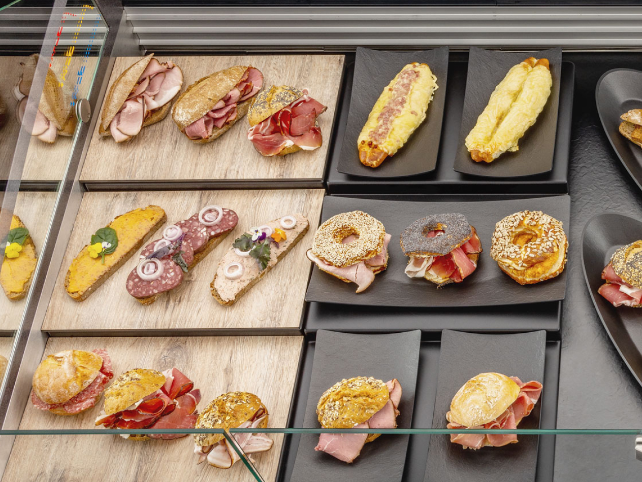 Ansprechende Präsentation von Snacks und belegtem Gebäck auf Thekenschalen in Holzoptik.